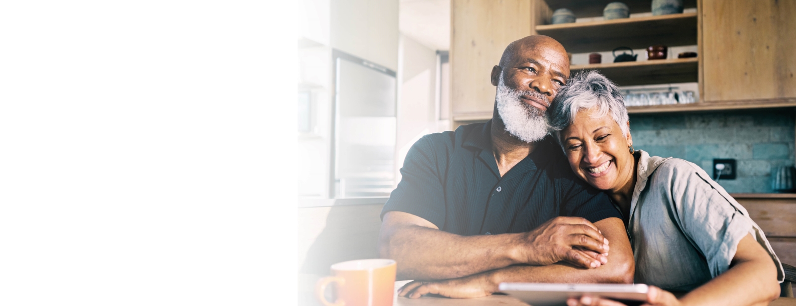 Happy elderly couple sitting in kitchen.