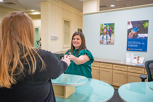A United Bank employee handing a credit card to a customer.