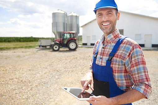 Farmer smiling into the camera with his farm in the background